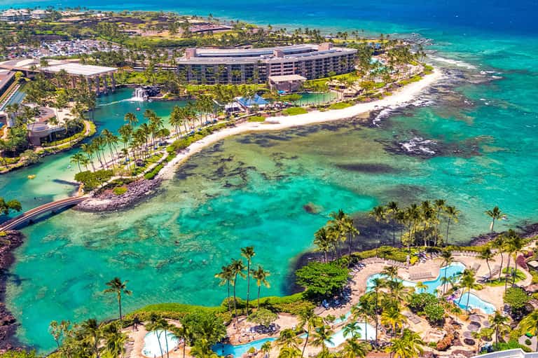 Aerial view of luxury resort on tropical peninsula with turquoise lagoon and palm-lined beach