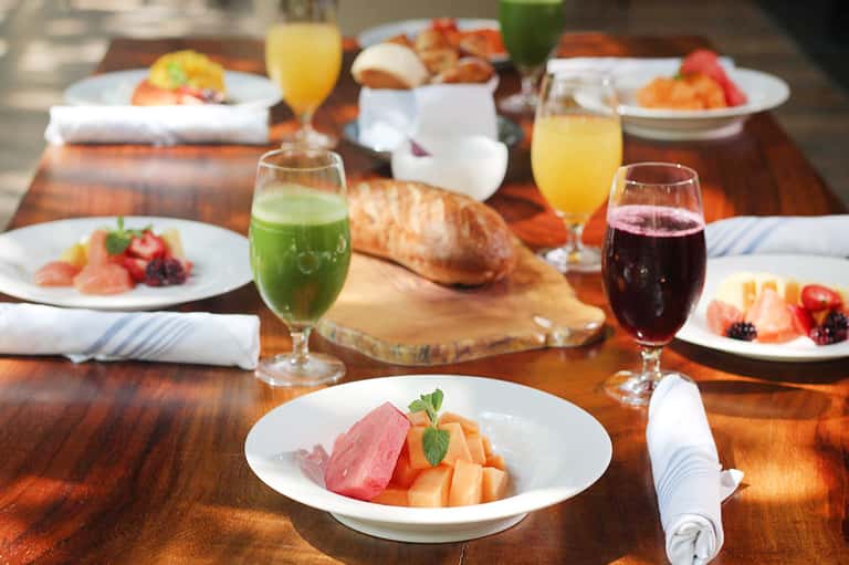 Formal dining table with plated food, wine glasses, bread, and fresh fruit