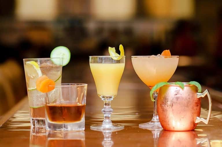 Colorful cocktails with fresh citrus garnishes displayed on a wooden bar counter