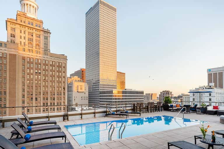 Urban rooftop pool overlooking downtown skyline with lounge chairs and city architecture