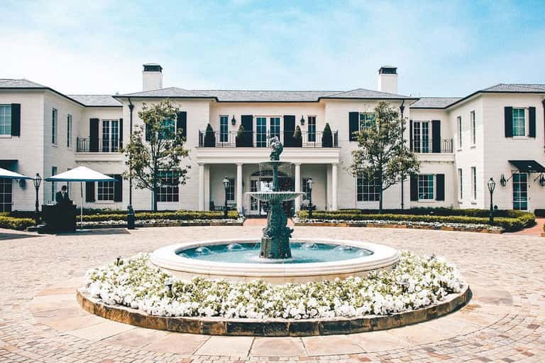 Elegant white mansion exterior with central fountain and manicured gardens