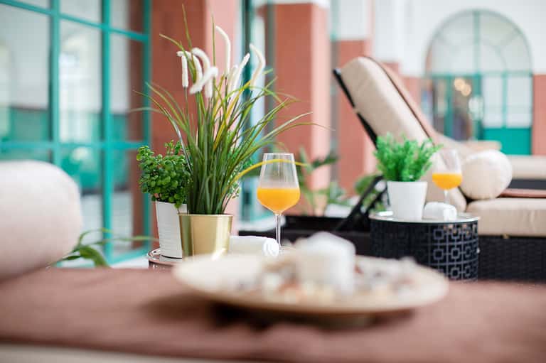 Poolside dining setup with tropical flowers, juice glass, and ocean-view terrace in background
