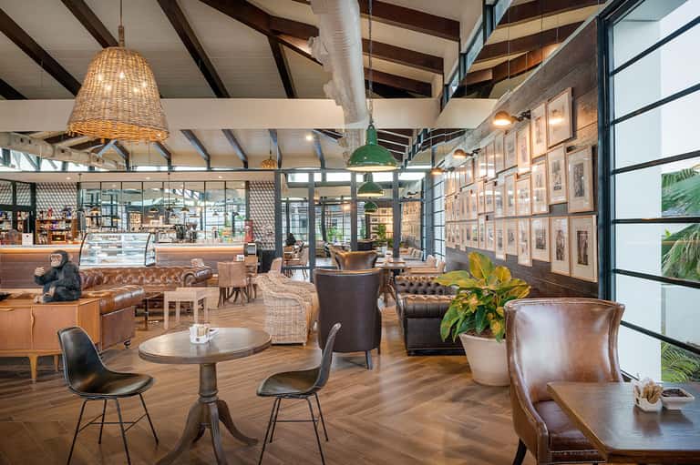 Modern hotel lobby with leather seating, woven pendant lights, exposed beams, and framed artwork on walls