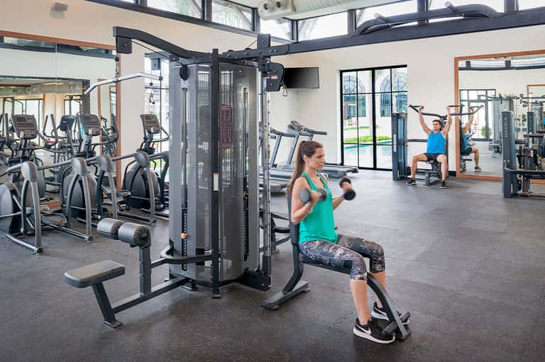 Modern fitness center with exercise equipment and woman doing dumbbell exercises