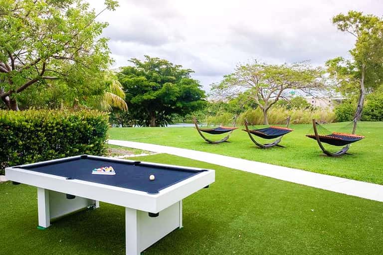 Lawn recreation area with pool table and hammocks under mature trees