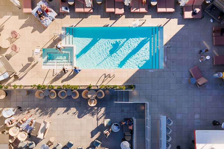 Aerial view of rectangular lap pool with turquoise water, surrounded by lounge chairs and patio
