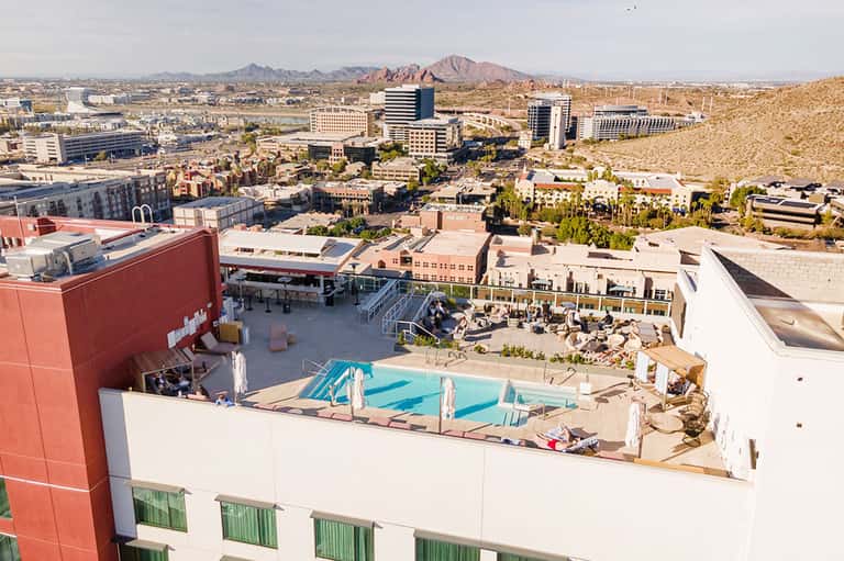 Rooftop pool and lounge area at desert resort with mountain views and surrounding urban landscape