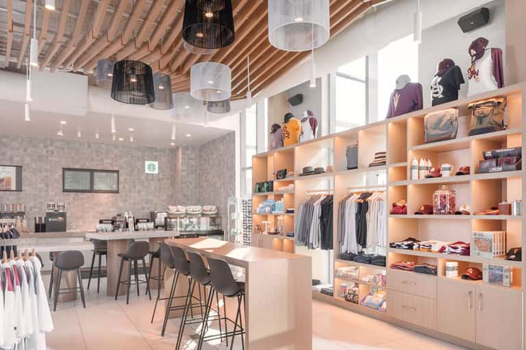 Modern retail boutique interior with orange shelving, clothing displays, café counter, and contemporary pendant lighting