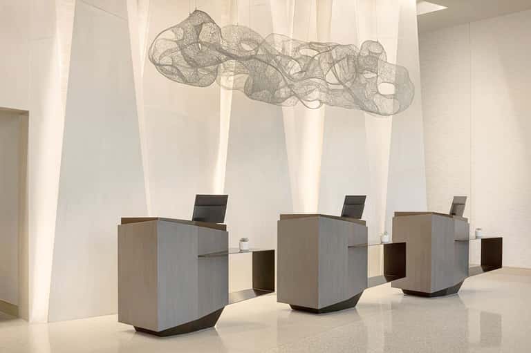 Modern hotel lobby with minimalist reception desks and hanging wire sculpture artwork
