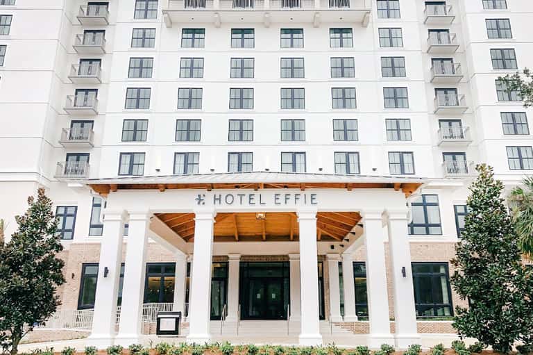 Hotel Effie white facade with wooden pergola entrance, brick accents and manicured landscaping