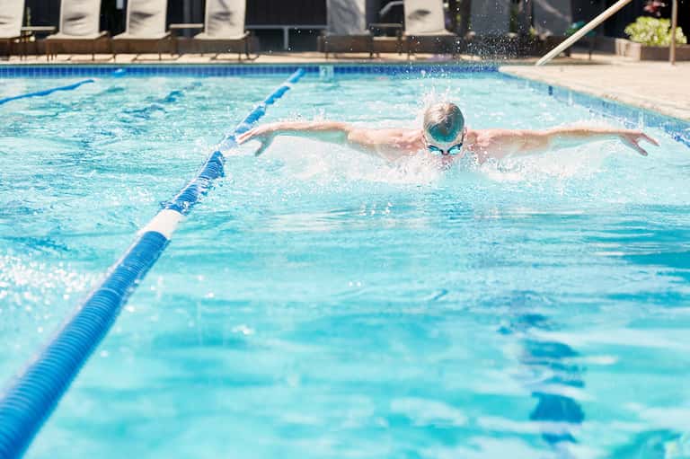 Competitive swimmer performing butterfly stroke in a blue lane-divided pool