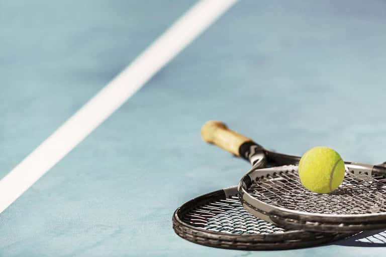 Tennis rackets with yellow ball on blue court with white line marking