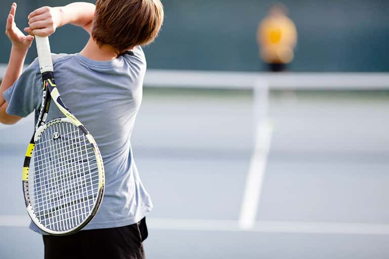 Young tennis player holding racket on court preparing to serve
