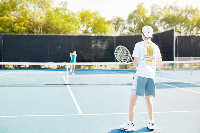 Tennis player on outdoor court during daytime match with spectators in background