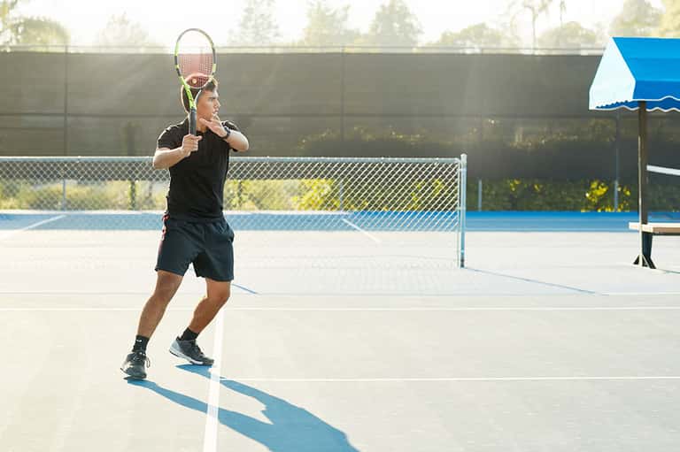 Tennis player in action on an outdoor blue court