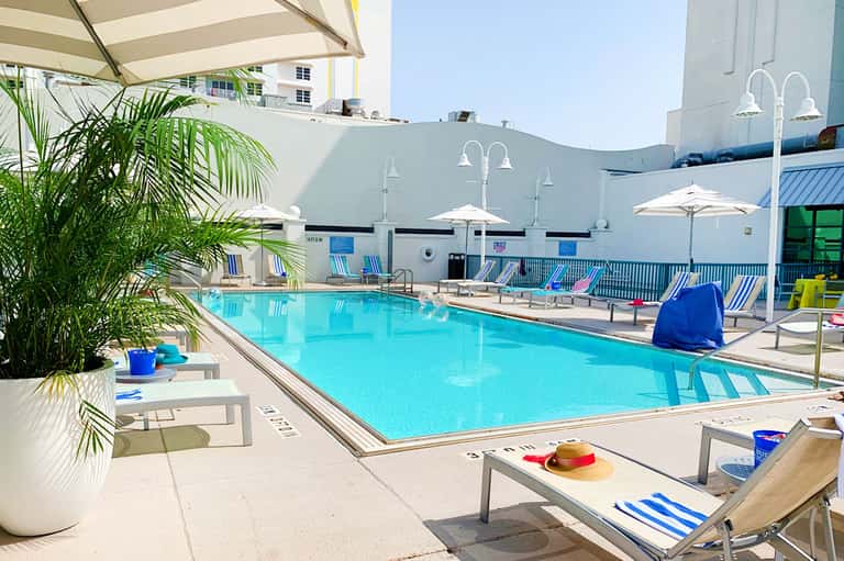 Resort swimming pool with blue and white striped loungers and white umbrellas
