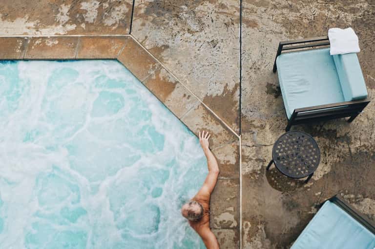 Overhead view of guest swimming in pool beside loungers on concrete patio