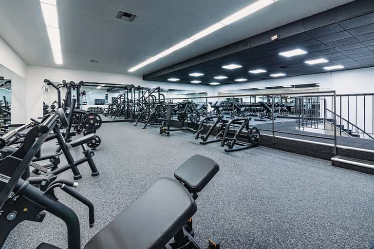 Modern fitness center with rows of stationary bikes and cardio equipment under bright ceiling lights
