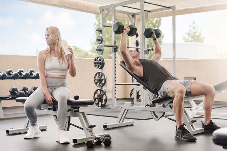 Rooftop gym with woman doing squats and man lifting dumbbells