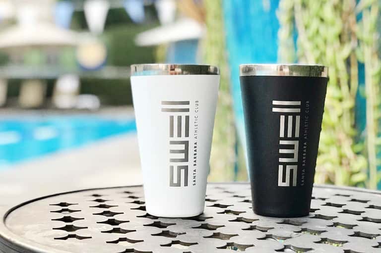 Two insulated travel cups with SWELL branding on patterned table by pool