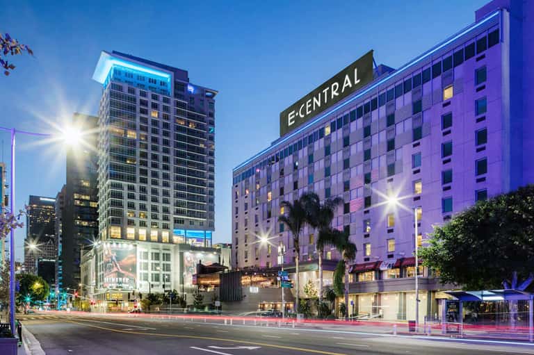 E'Central hotel building illuminated at dusk with purple lighting and palm trees on urban street
