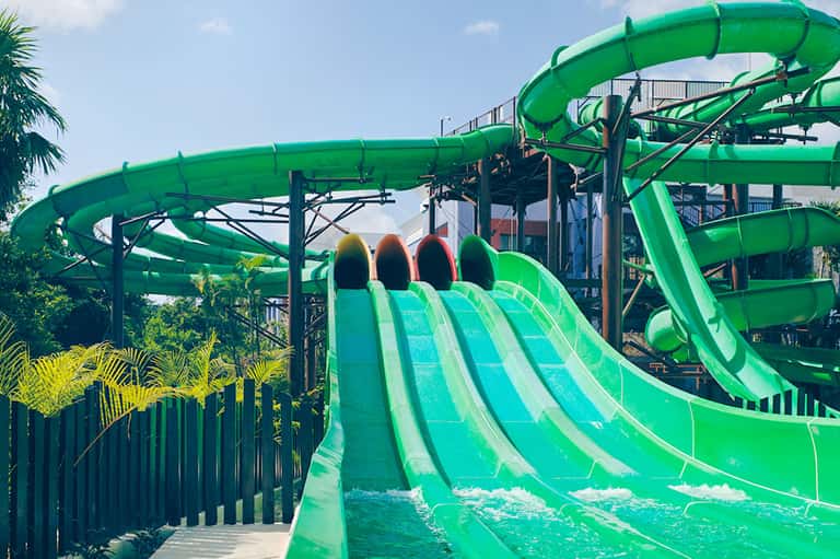 Water park with multiple bright green spiral water slides and tropical landscaping