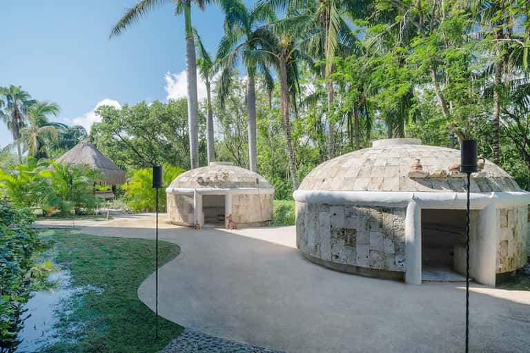 Concrete dome-shaped structures in lush tropical garden with palm trees and landscaping