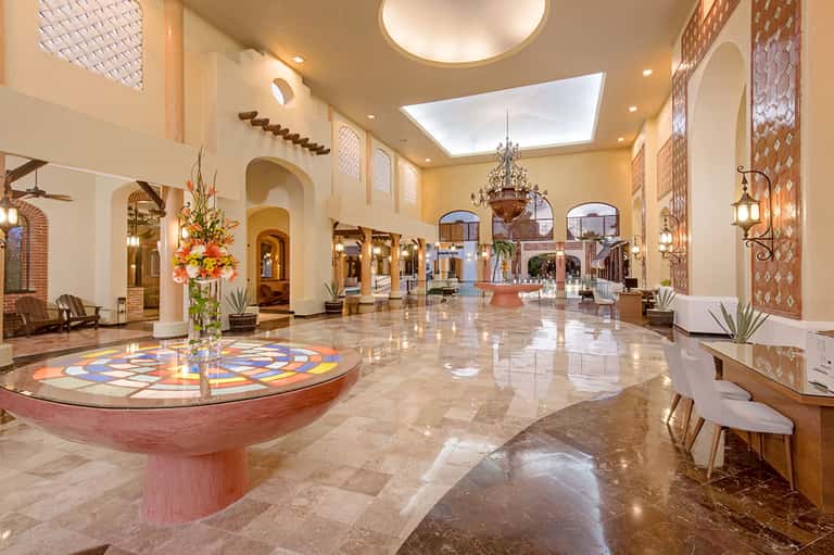 Elegant hotel lobby with high ceilings, chandelier, arched doorways, and decorative floor mosaic