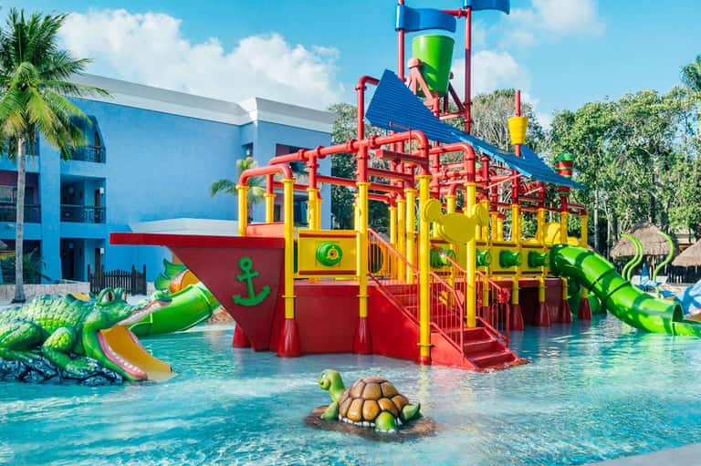 Colorful children's water playground with red and yellow structures in shallow pool