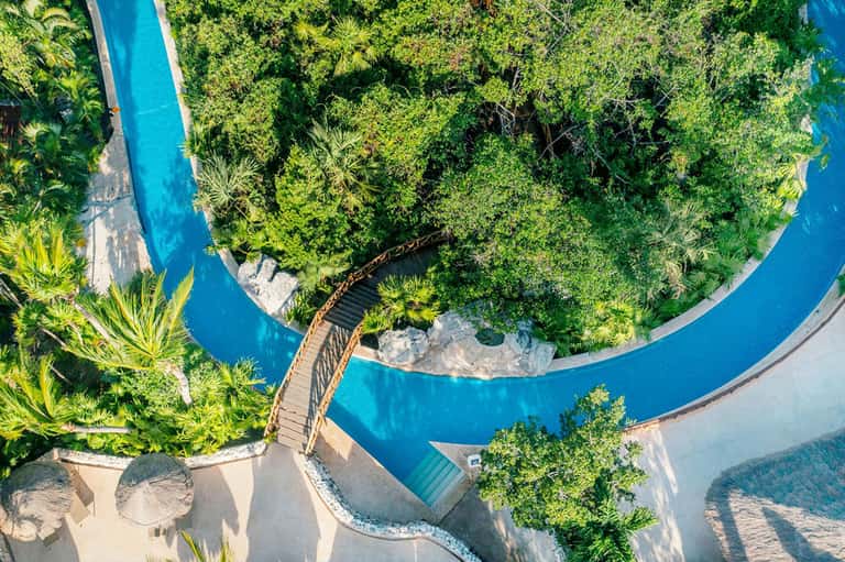 Aerial view of winding turquoise river through dense tropical vegetation