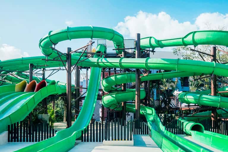 Bright green water slides at outdoor waterpark under clear blue sky