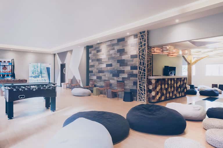Modern game room with foosball table, lounge seating, and geometric stone wall accent