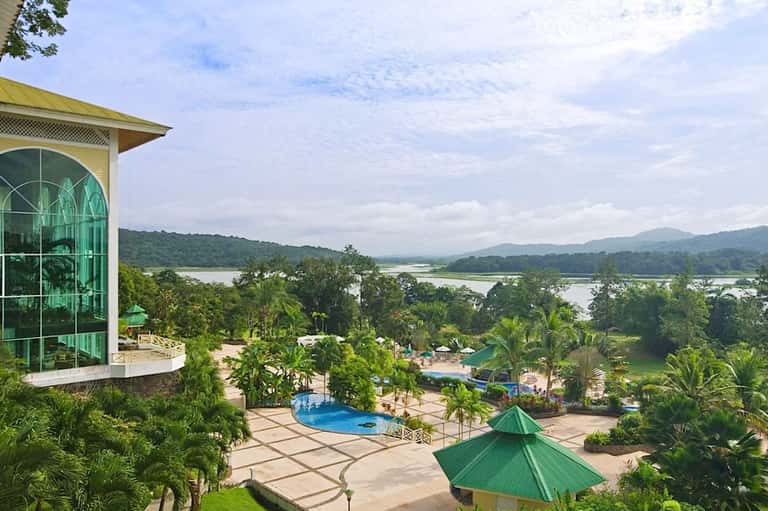 Aerial view of resort with pool, tropical grounds, and river landscape beyond