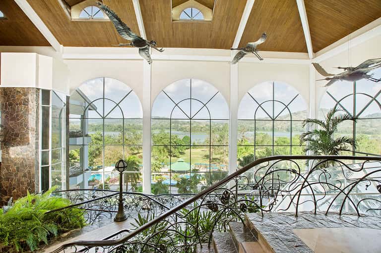 Upscale interior with arched windows, ornamental railings, and views of landscaped grounds and water