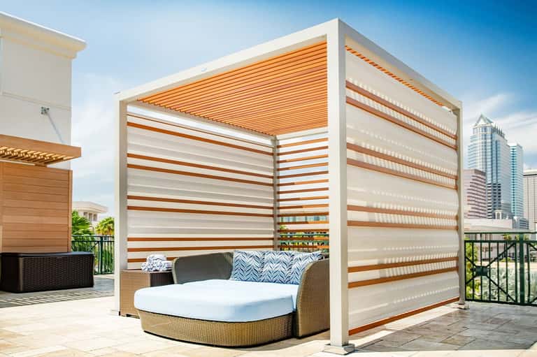Outdoor daybed with striped canopy on rooftop terrace overlooking city skyline