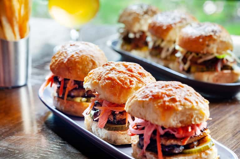 Slider sandwiches with red pickled vegetables served on black plate