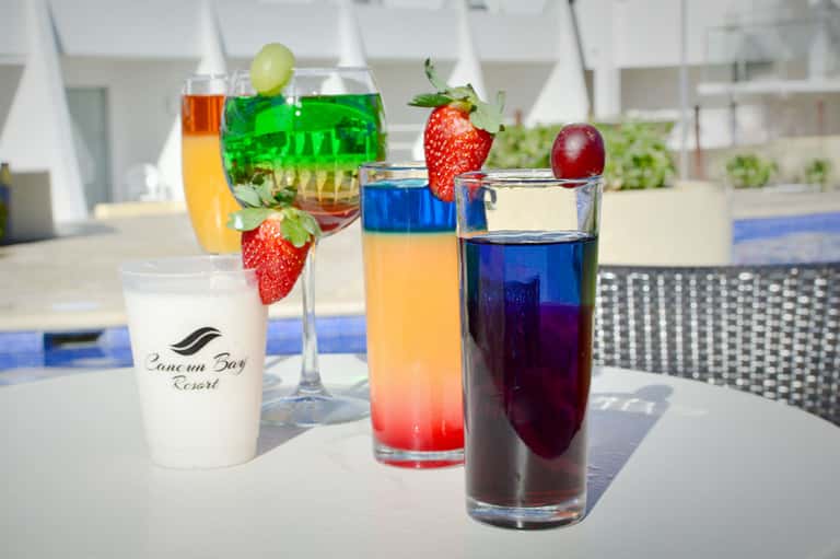 Colorful tropical cocktails with fresh strawberries and fruit garnishes on poolside table