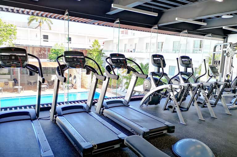 Fitness center with multiple treadmills overlooking an outdoor pool through glass windows