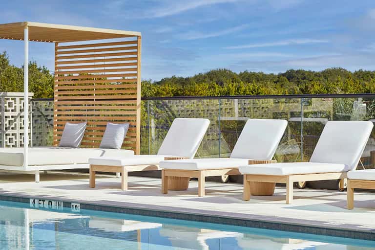 Poolside lounge chairs with umbrellas and wooden pergola shade structure