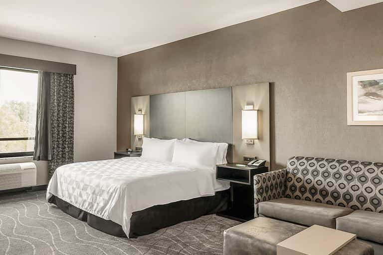 Modern hotel bedroom with white bedding, neutral walls, and contemporary furnishings