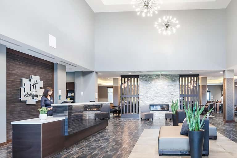 Contemporary hotel lobby with dark wood reception desk, modern lighting, and seating area