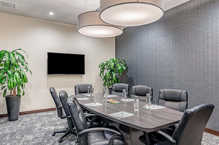 Professional conference room with long table, black chairs, and presentation screen