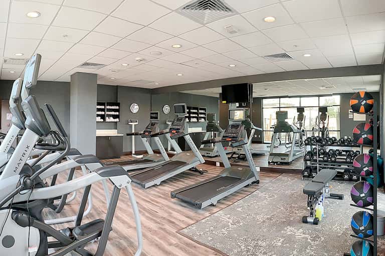 Modern hotel fitness center with treadmills, exercise equipment, and floor-to-ceiling windows