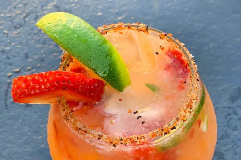 Colorful tropical cocktail with lime slice and spiced rim served poolside