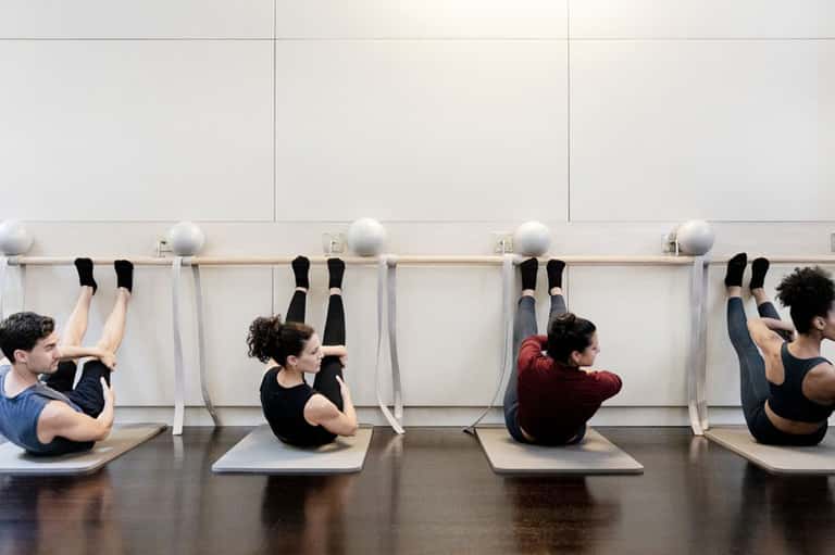 Group fitness class doing core exercises with stability balls against wall