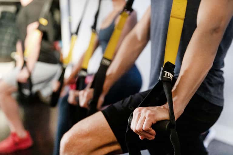 Group of people wearing TRX suspension training straps during fitness class