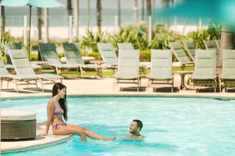 Couple enjoying resort pool with lounge chairs and ocean view in background