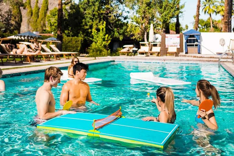 Children participating in water activities in a resort pool with floating platforms and instructors