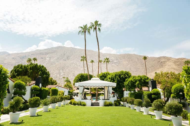 Elegant white gazebo on manicured lawn with desert mountains and palm trees in background