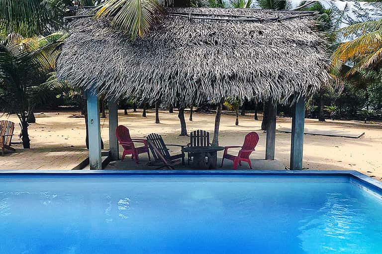 Tropical beach resort with thatched-roof cabana, lounge chairs, and turquoise pool